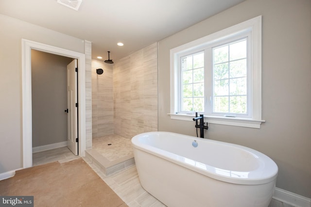 full bathroom featuring a soaking tub, baseboards, visible vents, and tiled shower