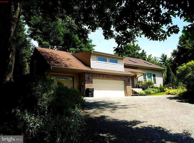 split level home with brick siding, driveway, and an attached garage