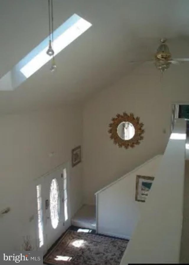 foyer with a skylight, high vaulted ceiling, and ceiling fan