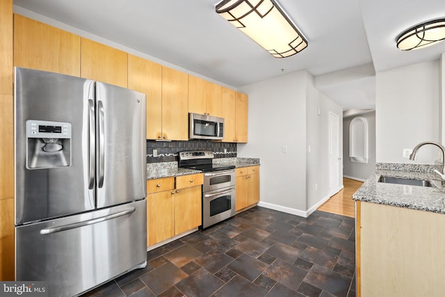 kitchen featuring appliances with stainless steel finishes, tasteful backsplash, a sink, and light stone countertops