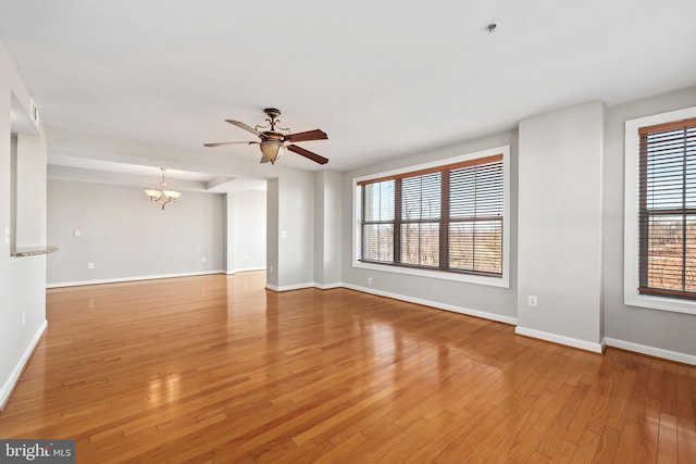 spare room with light wood-type flooring, baseboards, and ceiling fan with notable chandelier