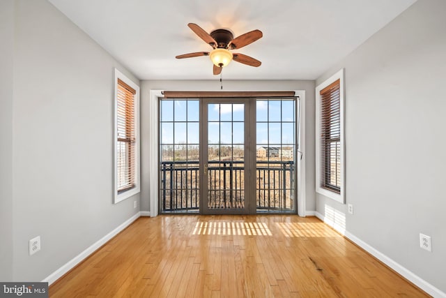 empty room featuring light wood-type flooring, baseboards, and a ceiling fan