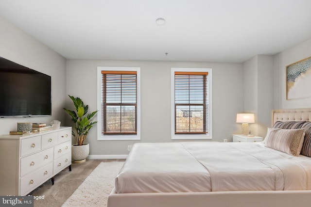 bedroom with light colored carpet, baseboards, and multiple windows