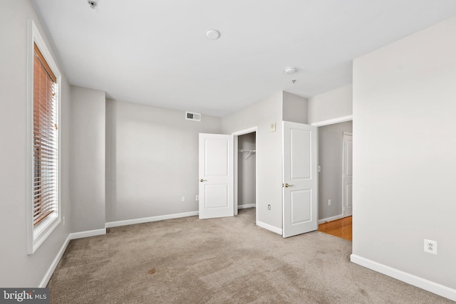 unfurnished bedroom featuring light carpet, a closet, visible vents, and baseboards