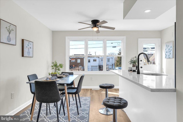 dining space featuring ceiling fan, wood-type flooring, and sink