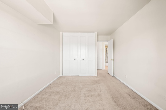 unfurnished bedroom with light carpet and a closet