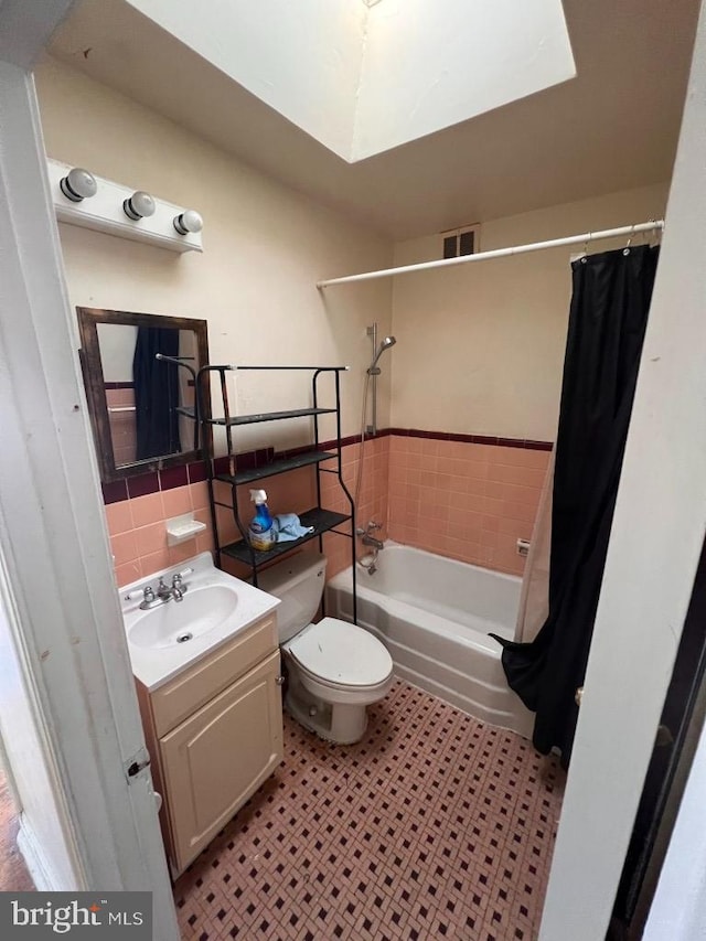 full bathroom with shower / bathtub combination with curtain, tile walls, vanity, decorative backsplash, and toilet