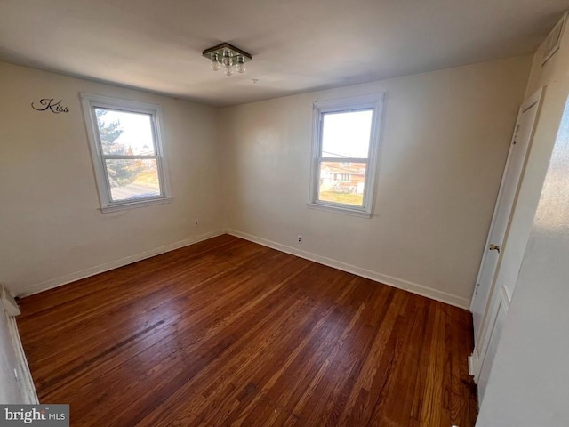 empty room featuring plenty of natural light and dark hardwood / wood-style floors