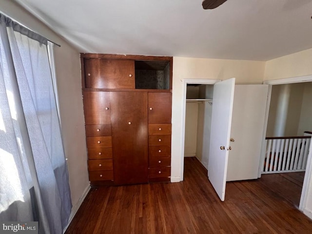 unfurnished bedroom with dark wood-type flooring and a closet