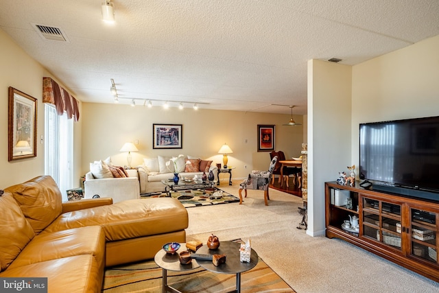 living area with carpet, track lighting, visible vents, and a textured ceiling