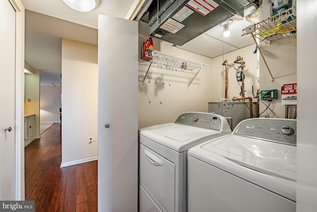 laundry room featuring water heater, laundry area, wood-type flooring, and washing machine and dryer