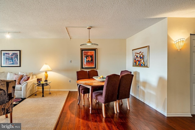 dining space with wood-type flooring, rail lighting, a textured ceiling, and baseboards