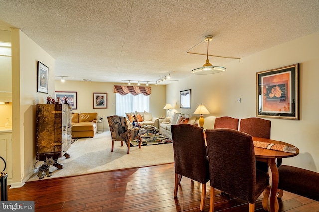 dining area featuring rail lighting, a textured ceiling, and hardwood / wood-style floors