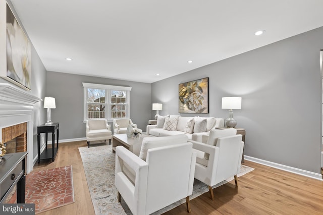 living room with a brick fireplace and light wood-type flooring