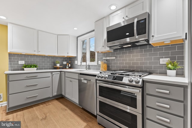 kitchen featuring gray cabinetry, stainless steel appliances, and white cabinets