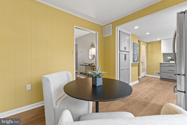 dining space featuring crown molding and light wood-type flooring