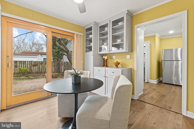 dining space featuring ceiling fan, ornamental molding, and light wood-type flooring