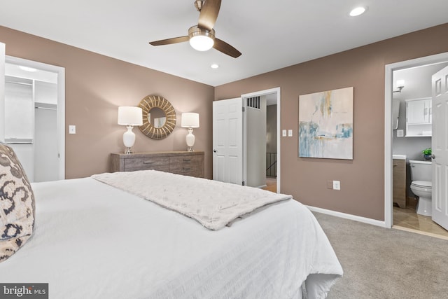 bedroom featuring ceiling fan, light colored carpet, ensuite bathroom, and a spacious closet