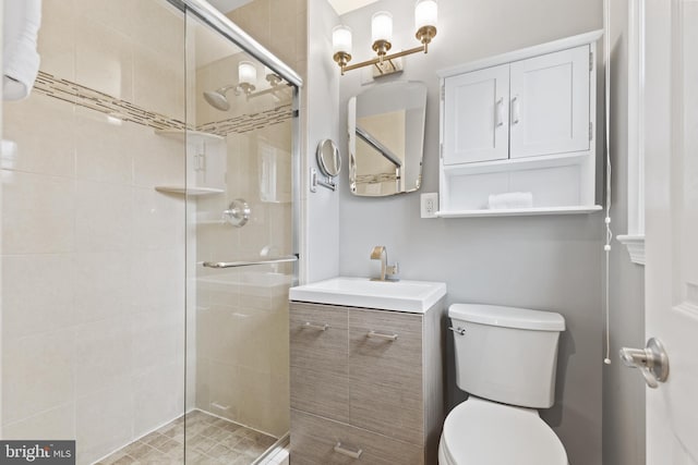 bathroom featuring vanity, a shower with shower door, and toilet