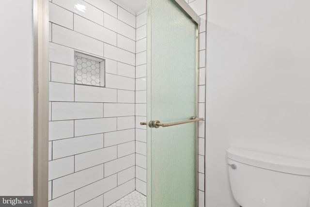 bathroom featuring a shower with shower door and toilet