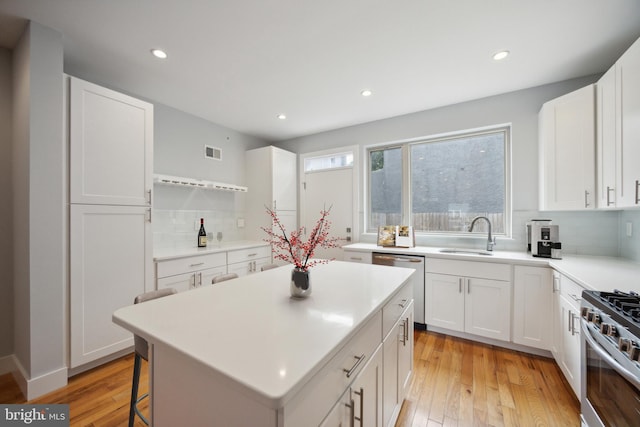 kitchen featuring appliances with stainless steel finishes, sink, a center island, white cabinetry, and tasteful backsplash