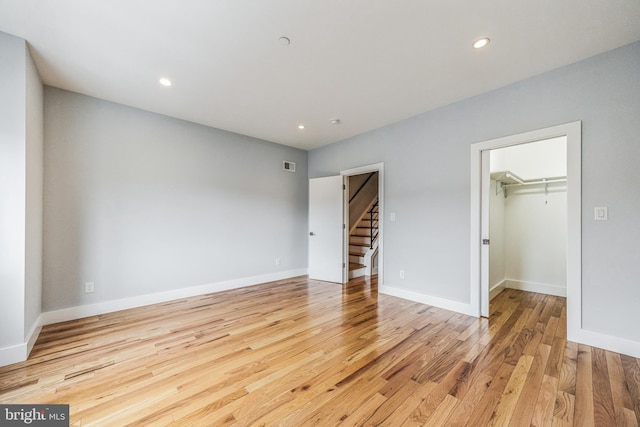 unfurnished bedroom with light wood-type flooring, a closet, and a walk in closet