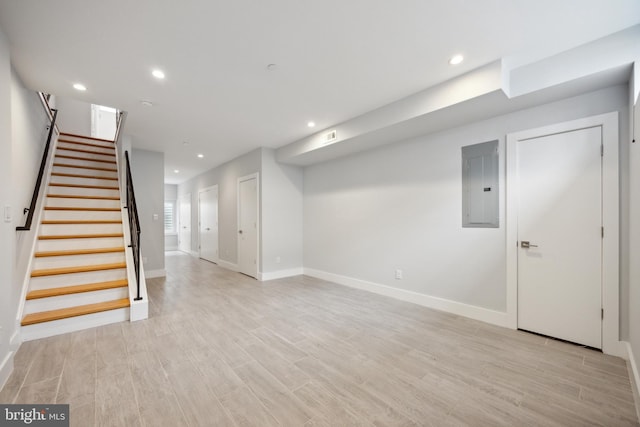 basement with light hardwood / wood-style floors and electric panel