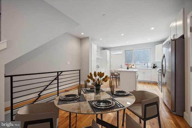 kitchen with light hardwood / wood-style flooring, a kitchen island, sink, appliances with stainless steel finishes, and white cabinets