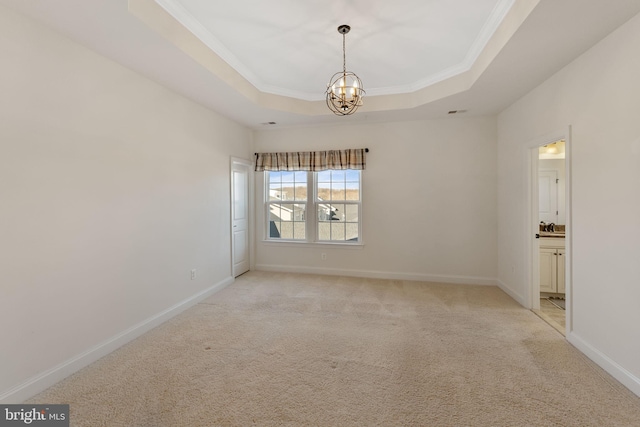 carpeted spare room featuring ornamental molding, an inviting chandelier, and a raised ceiling