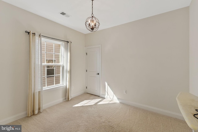 carpeted spare room featuring a notable chandelier