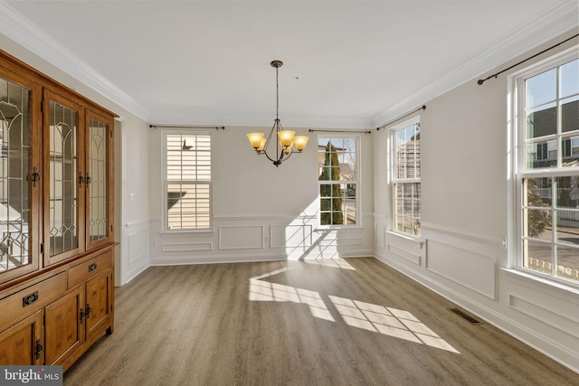 unfurnished dining area featuring an inviting chandelier, plenty of natural light, and ornamental molding