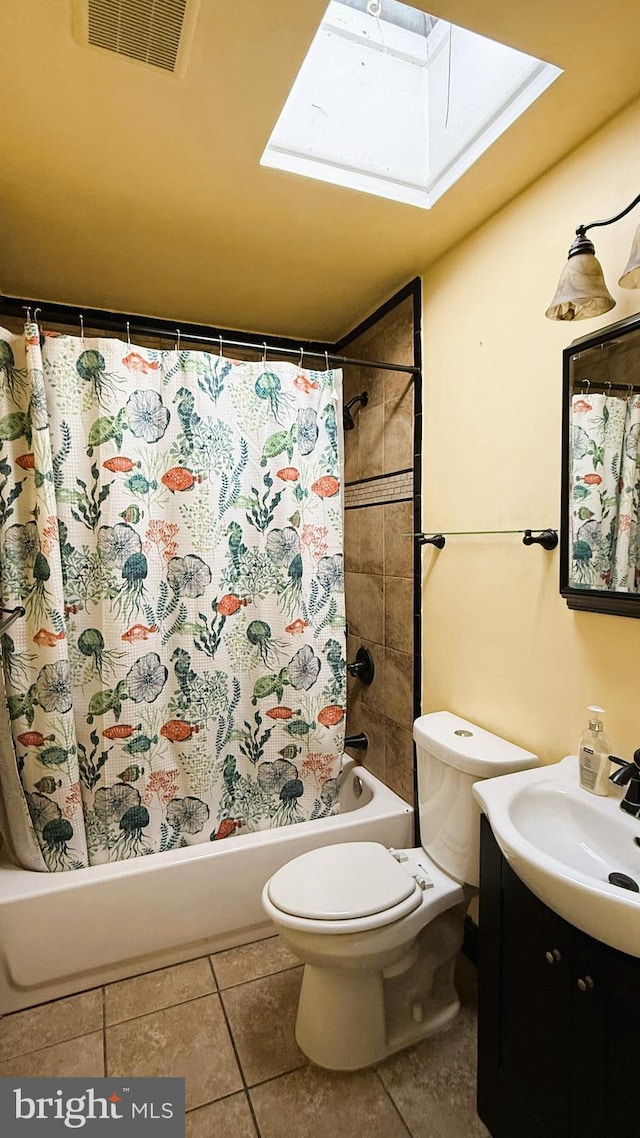 full bathroom featuring a skylight, vanity, shower / bath combination with curtain, tile patterned floors, and toilet