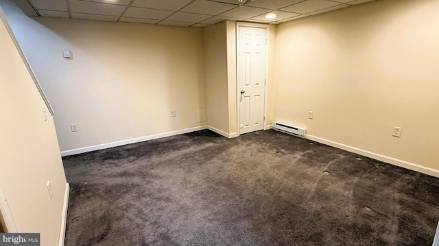 carpeted spare room featuring a drop ceiling and a baseboard heating unit