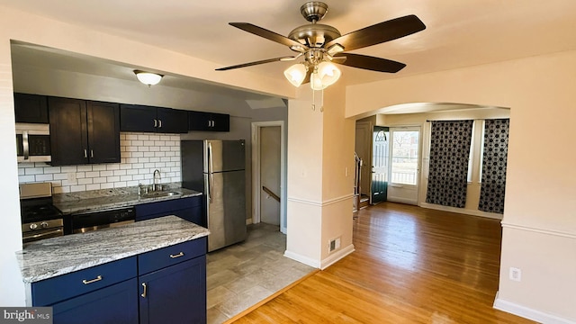 kitchen featuring sink, ceiling fan, appliances with stainless steel finishes, tasteful backsplash, and light hardwood / wood-style floors