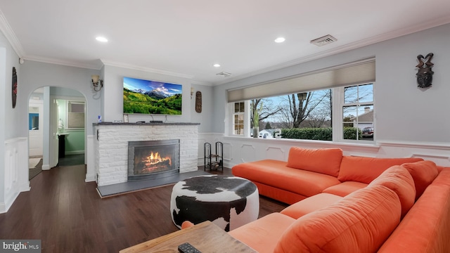 living room with dark hardwood / wood-style flooring, crown molding, and a fireplace