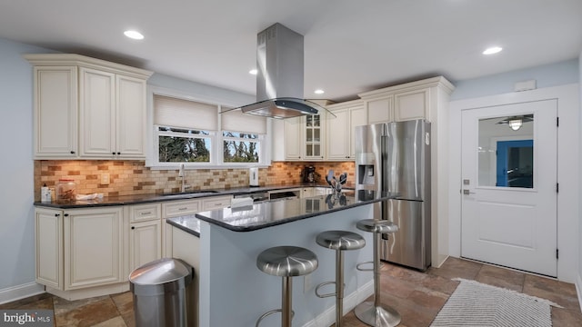 kitchen with sink, backsplash, island range hood, a kitchen island, and stainless steel fridge with ice dispenser