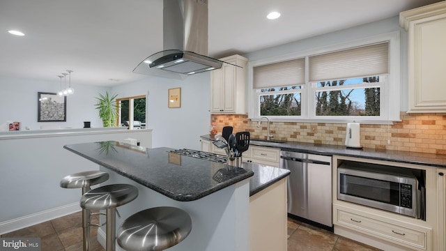 kitchen with a breakfast bar area, appliances with stainless steel finishes, a center island, island range hood, and decorative light fixtures