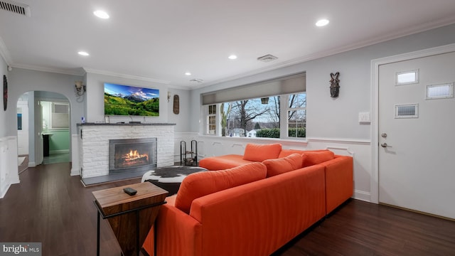 living room with dark hardwood / wood-style flooring, a brick fireplace, and ornamental molding