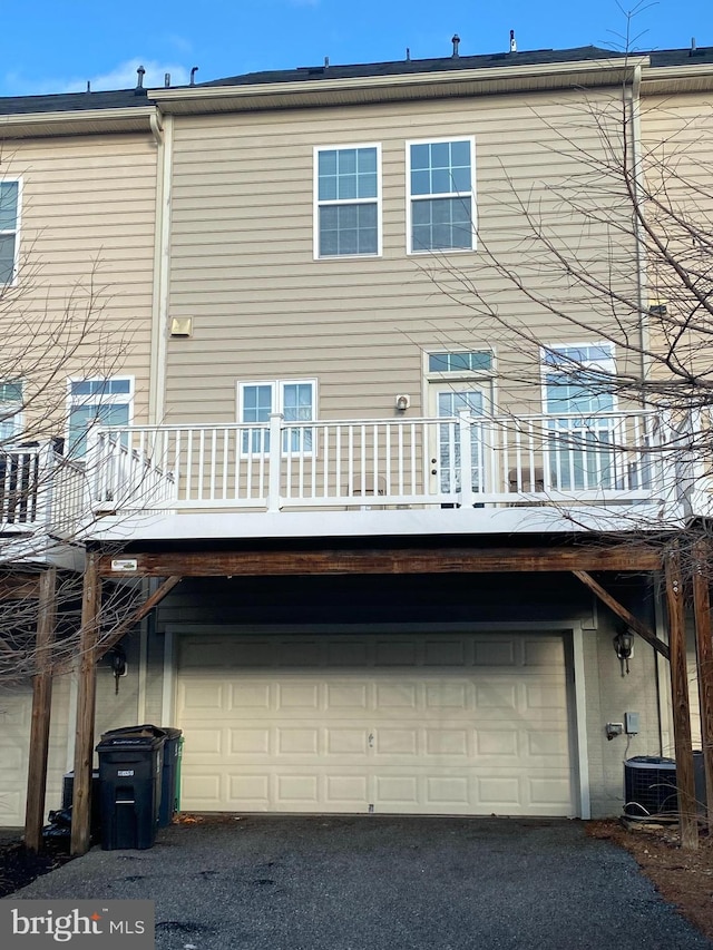 rear view of property with cooling unit and a garage