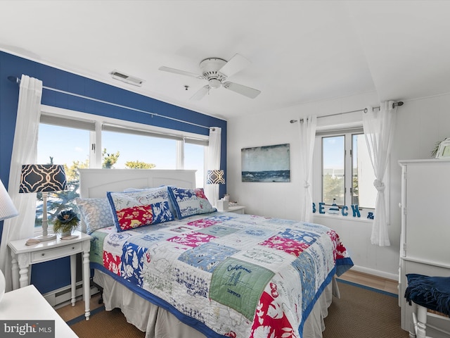 bedroom with ceiling fan, multiple windows, dark hardwood / wood-style flooring, and a baseboard radiator