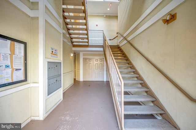 stairs with mail boxes, concrete floors, and a high ceiling