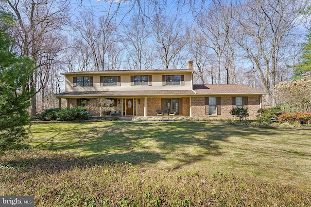 view of front of house featuring brick siding, a chimney, and a front yard