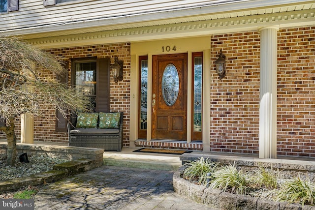 property entrance with brick siding and a porch