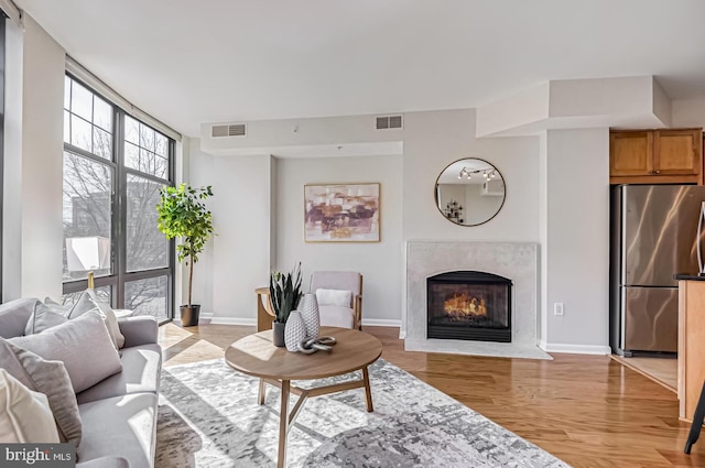 living room featuring expansive windows, a premium fireplace, and light hardwood / wood-style floors