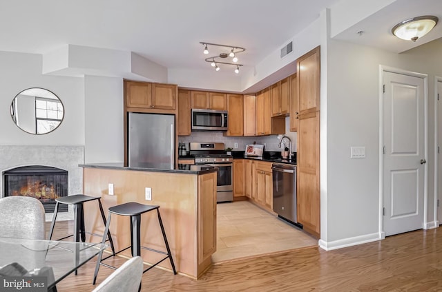 kitchen with sink, appliances with stainless steel finishes, kitchen peninsula, a tiled fireplace, and backsplash