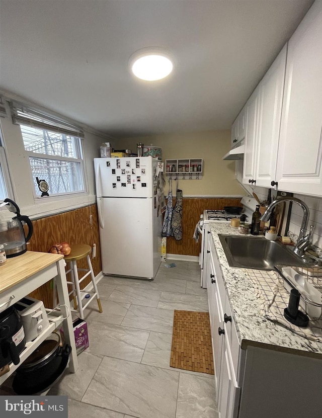 kitchen featuring sink, light stone counters, white refrigerator, stove, and white cabinets