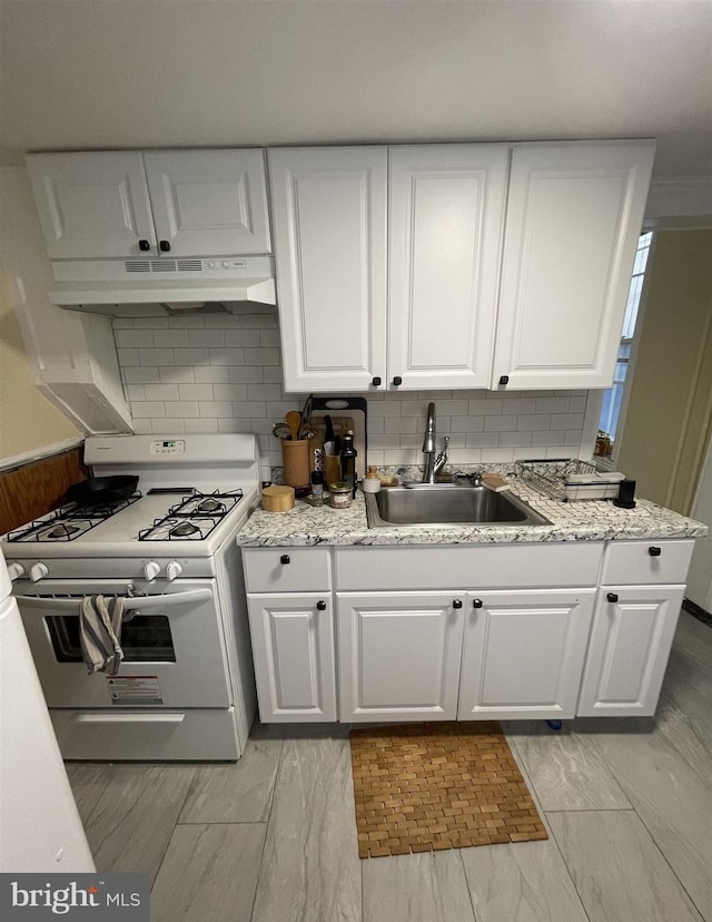 kitchen featuring tasteful backsplash, white cabinets, sink, and white gas stove