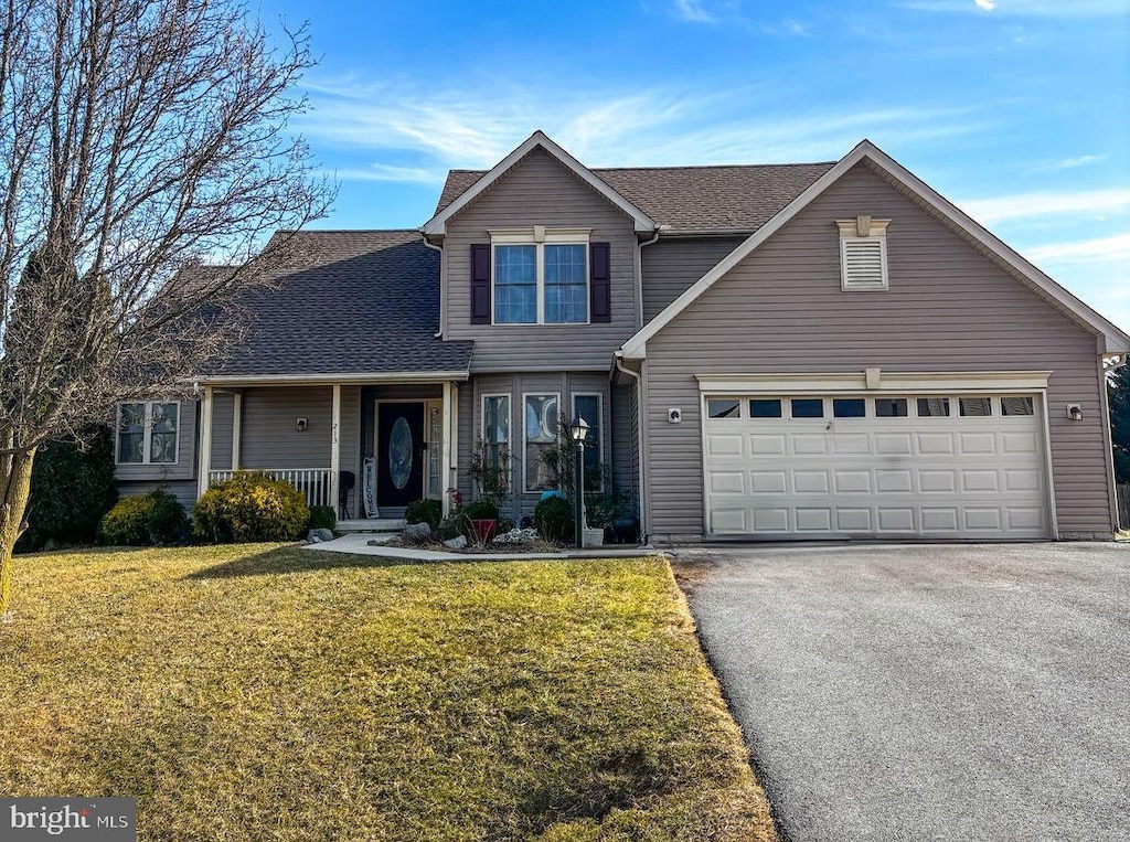 view of property with a garage, a porch, and a front yard