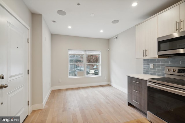 kitchen with stainless steel appliances, light hardwood / wood-style flooring, and decorative backsplash