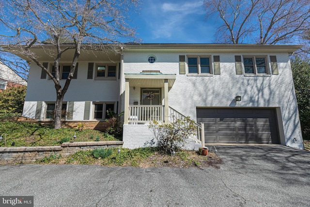 bi-level home with brick siding, an attached garage, and aphalt driveway